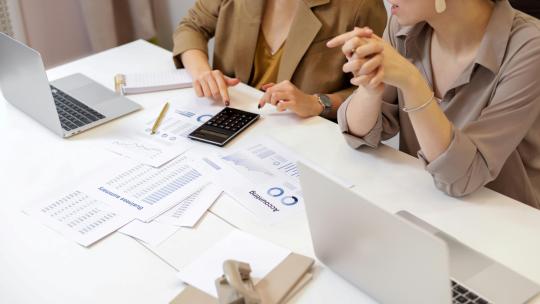 dos-mujeres-trabajando-en-una-base-de-datos-relacional-con-ordenadores-informes-y-calculadora