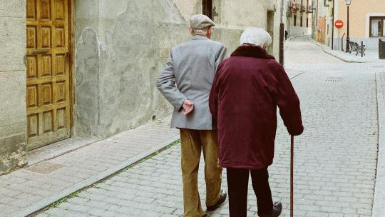 Hombre y mujer caminando cerca de una puerta de madera cerrada - @pzlvrs en Unsplash