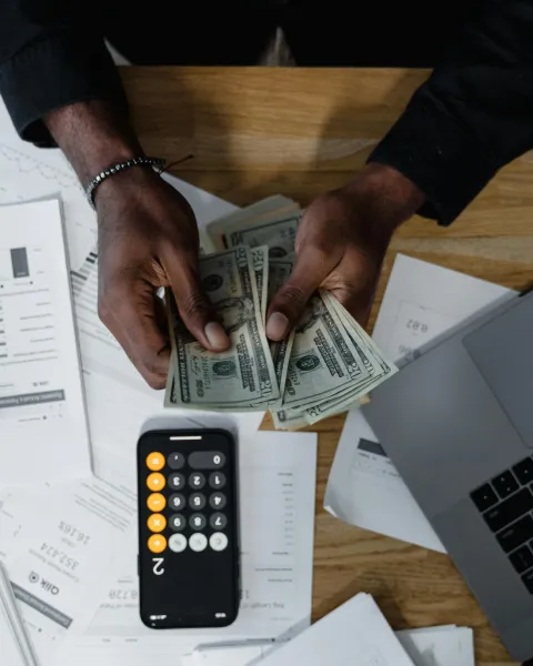 manos-de-una-persona-contando-billetes-de-euros-sobre-una-mesa-con-graficos-y-un-portatil-que-representan-el-sueldo-experto-ia